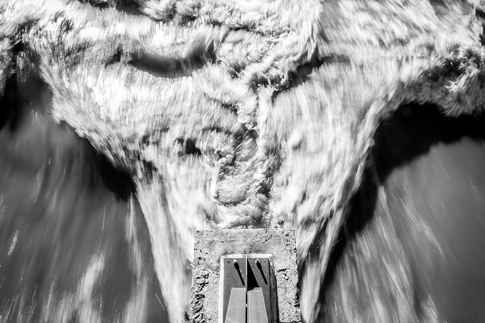 Abstract Of Turbulent Flood Water Rushing Past Bridge Piling In